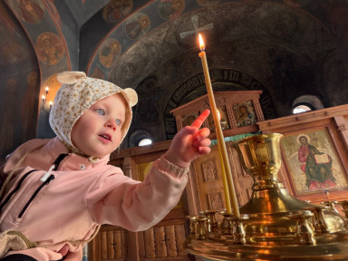 Ребенок тянет пальчик к свечке