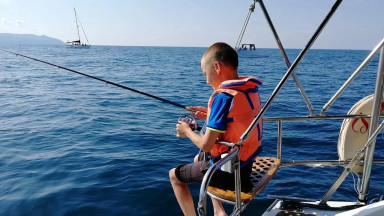 Мальчик ловит рыбу с яхты, в море