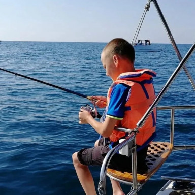 Мальчик ловит рыбу с яхты, в море