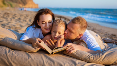 Семья читает книгу на берегу моря