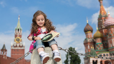 Девочка изучает карту через лупу, сидя на Красной Площади